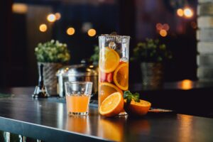 lemonade from orange and berries in two modern glasses in the form of a can and a carafe on a table.